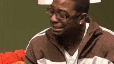 a man with glasses and a brown jacket is crying .