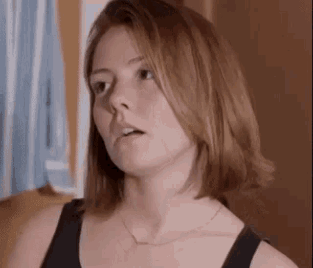 a close up of a woman wearing a necklace and a tank top .