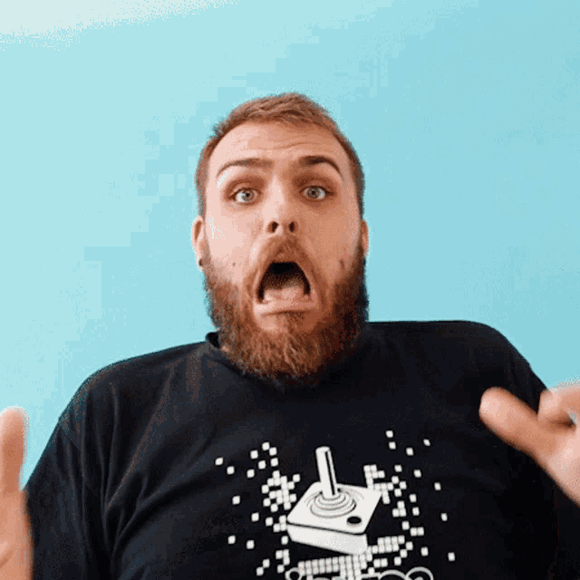 a man with a beard is wearing a black t-shirt with an atari joystick on it