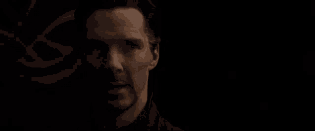 a close up of a man 's face with the words `` okay '' written on it in a dark room .