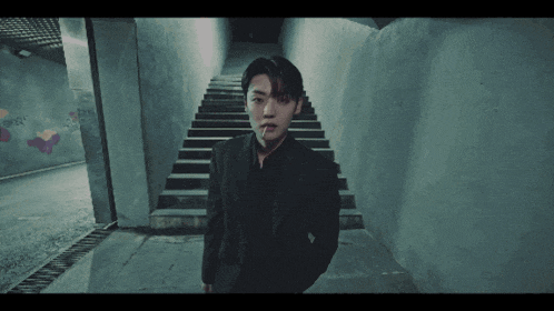 a man in a suit smoking a cigarette in a dark tunnel