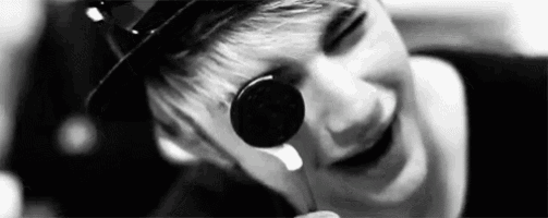 a black and white photo of a man eating a oreo cookie .