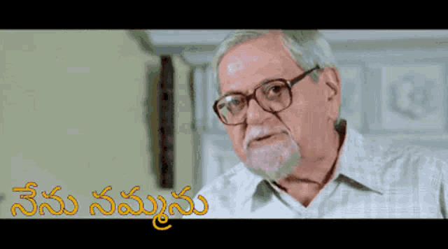 a man with glasses and a beard is standing in front of a sign that says ' telugu ' in yellow