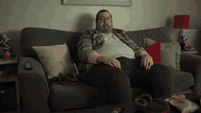 a man sits on a couch with a coke can on the couch