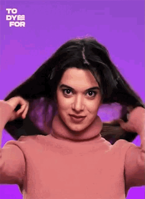 a woman in a pink turtleneck sweater is holding her hair .