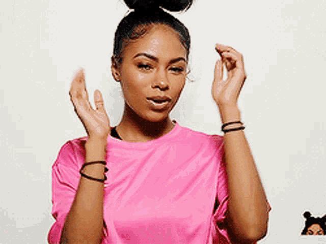 a woman in a pink shirt is holding her hands together