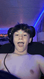 a shirtless young man is sitting in a chair with his tongue hanging out