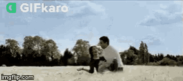 a man and a woman are sitting on top of a sandy field .