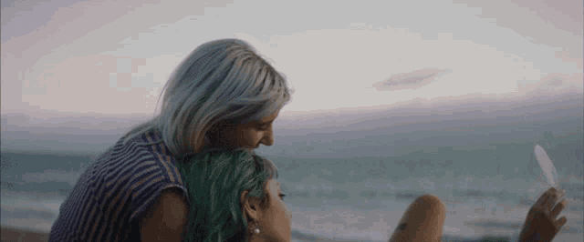 a woman with green hair is sitting next to another woman