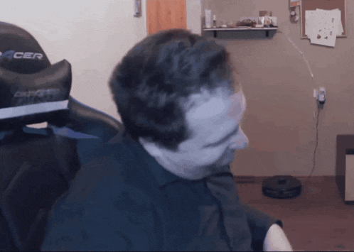 a man in a black shirt is sitting in a black acer gaming chair
