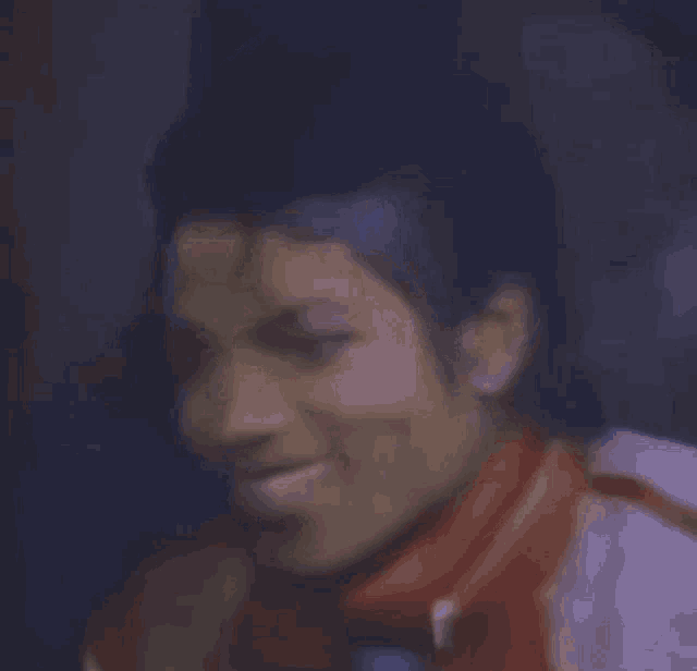 a close up of a man 's face with a red jacket and tie .