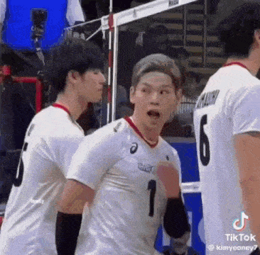 two volleyball players are standing next to each other on a court .