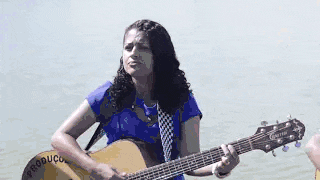 a man is playing an accordion and a woman is playing a guitar while a boy plays a guitar .
