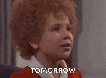 a little girl with red curly hair is smiling and saying tomorrow .