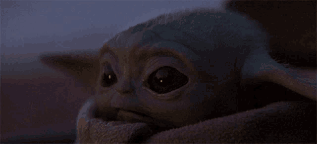 a close up of a baby yoda in a dark room