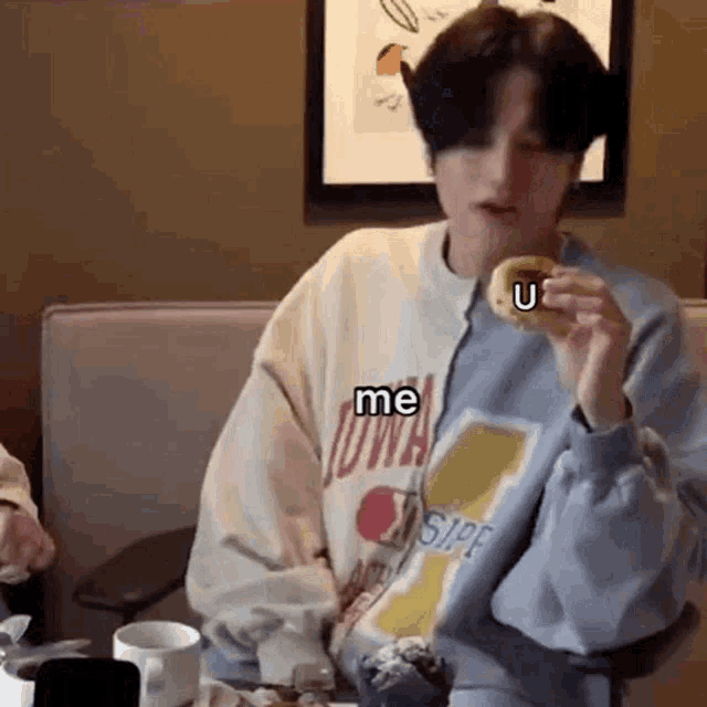 a man is sitting at a table eating a donut with the words `` me u '' on it .