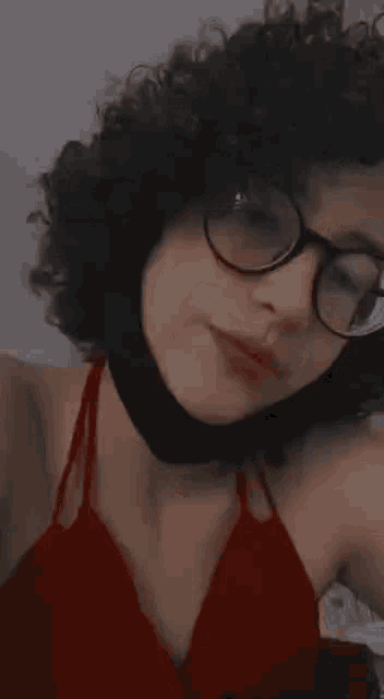 a woman with curly hair wearing glasses and a red top