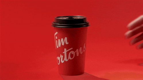 a person holding a red tim hortons cup