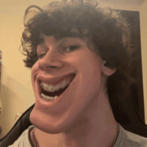 a young man with curly hair is making a funny face with his mouth open .