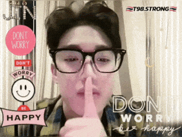 a man wearing glasses holds his finger to his lips and says " do n't worry be happy "