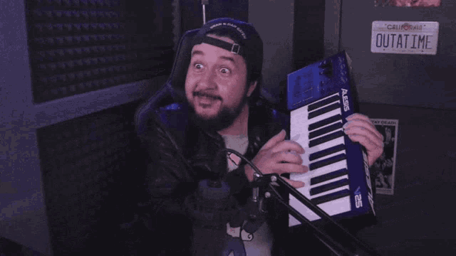 a man wearing a hat that says dean & dan caleb is holding an alesis keyboard