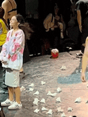 a group of people are standing on a stage with a lot of papers on the floor