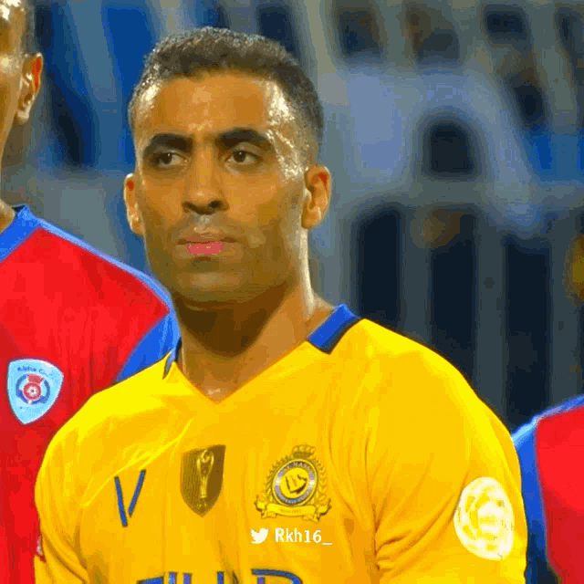 a soccer player wearing a yellow jersey with rkh16 on the bottom