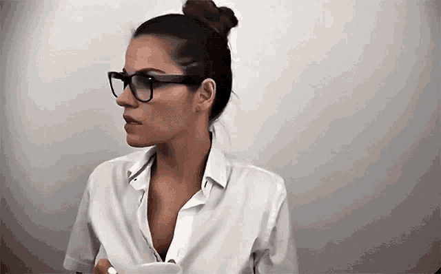 a woman wearing glasses is holding a cup of coffee