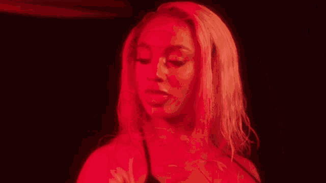 a close up of a woman 's face with red lights behind her .