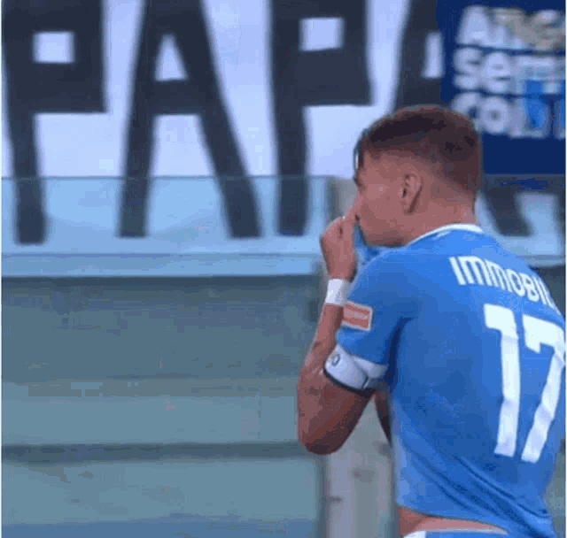 a soccer player wearing number 17 wipes his face with his hand