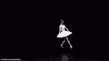 a black and white photo of a ballerina in a white tutu dancing on a stage .