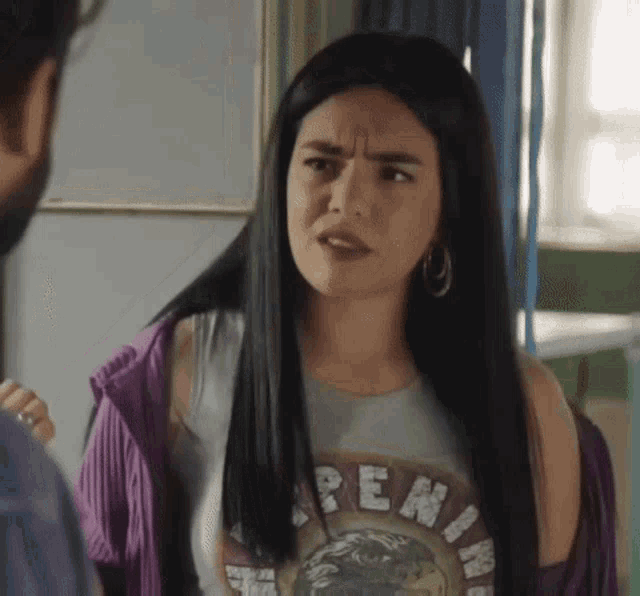 a woman with long black hair is making a funny face while talking to a man in a room .