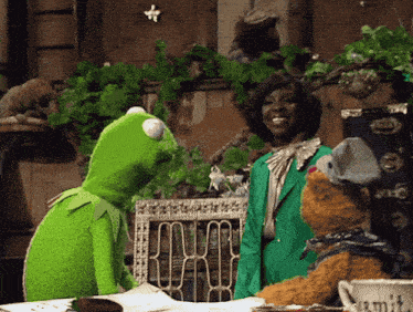 kermit the frog talks to a woman in a green suit