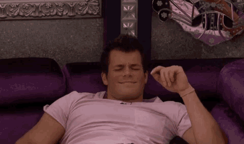 a man laying on a purple couch with his eyes closed