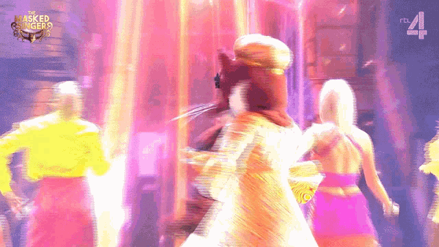 a group of people are dancing in front of a sign that says the masked singer on it