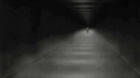 a person in a white shirt is standing in a dark room