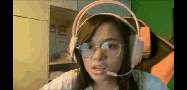 a woman wearing headphones and glasses is looking at the camera .