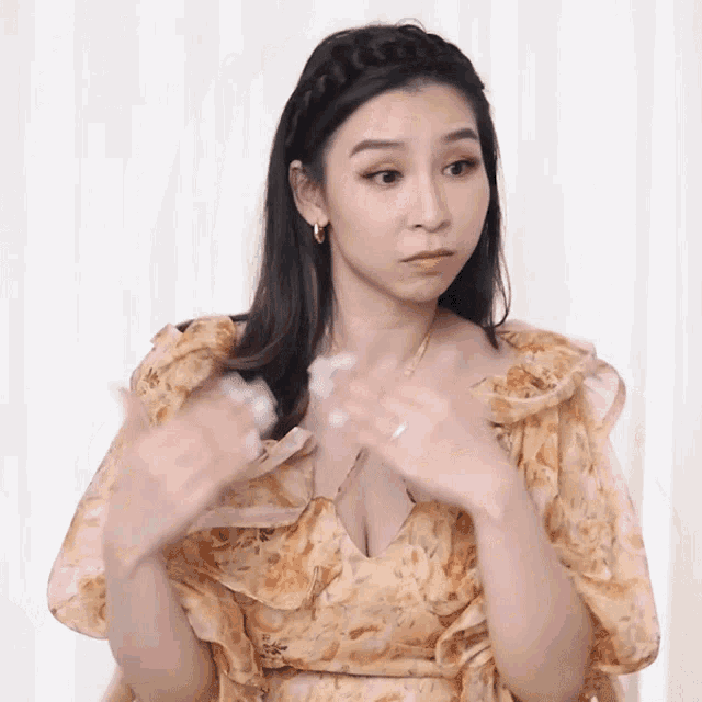 a woman in a yellow floral dress is making a face