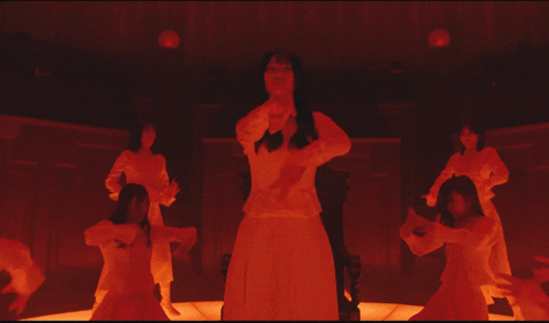 a woman in a white dress is surrounded by hands in red light