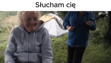 a woman in a wheelchair is standing next to another woman in a blue jacket in front of a tent .