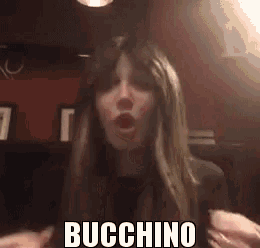 a woman is making a funny face with her mouth open and the word buchino written on her face .