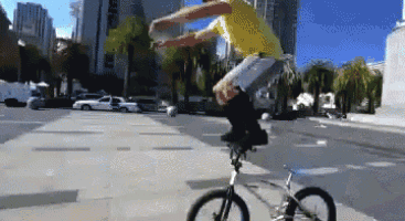 a man in a yellow shirt is riding a bike on a street