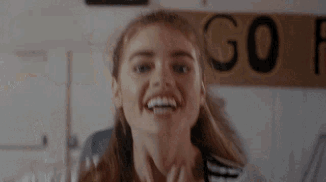 a girl is smiling in front of a sign that says " go "