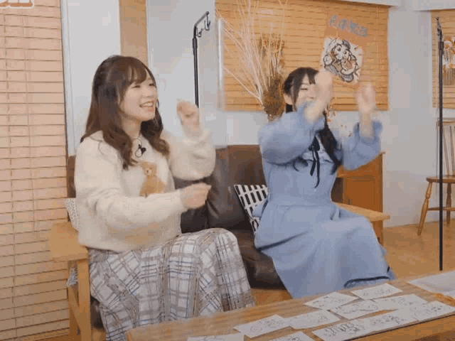two women sitting on a couch with their arms in the air