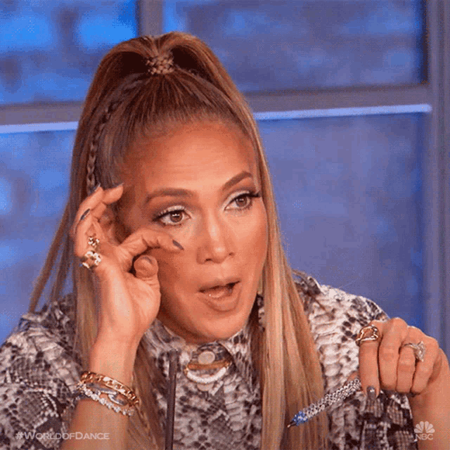 a woman with a ponytail and a snake print shirt is holding a pen in her hand .