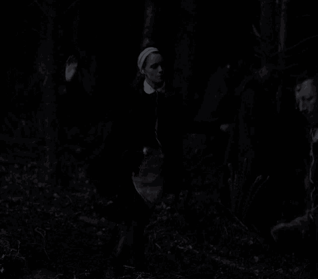 a woman in a maid outfit is dancing in a dark forest