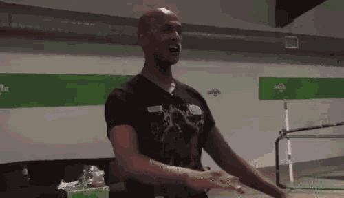a man in a black shirt is standing in front of a green and white wall .