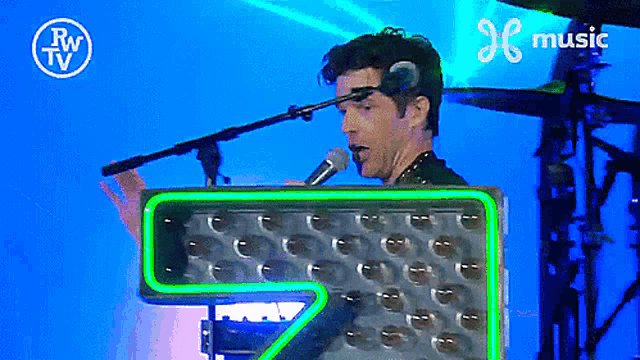 a man singing into a microphone in front of a sign that says music