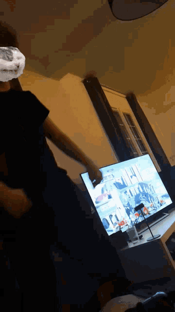 a man is standing in front of a television with a picture of a boat on it