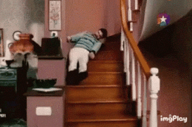 a man is falling down a set of wooden stairs in a living room
